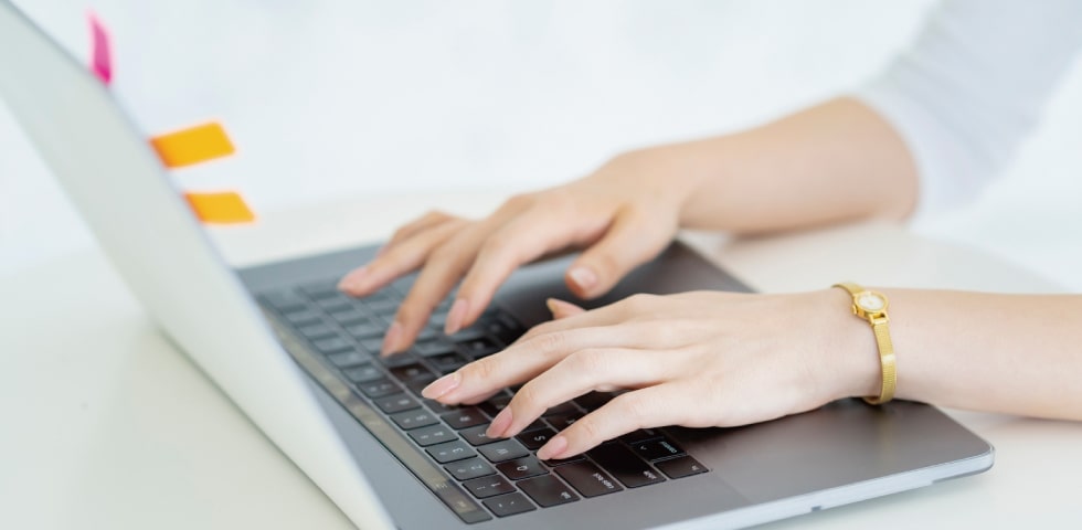 ノートパソコンでタイピングしている女性の手